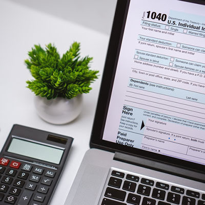 A laptop on a desk with a calculator beside it.