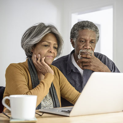 Senior African American couple using laptop, contemplating