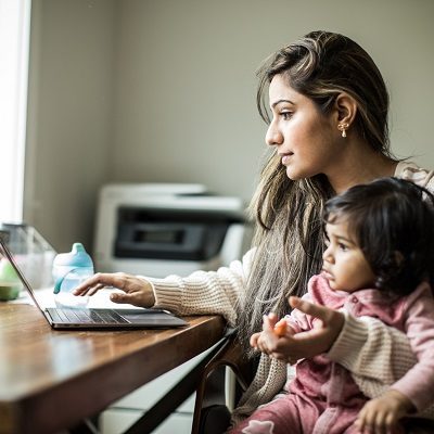 Mother multi-tasking with infant daughter in home office