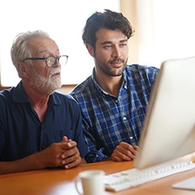 an older adult and younger adult working together at a computer screen