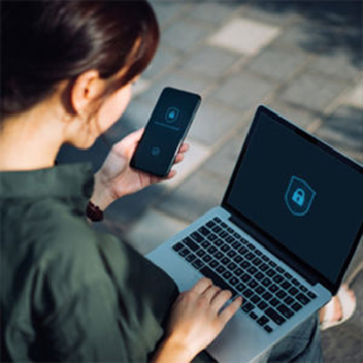 person reviewing information on smartphone and laptop computer