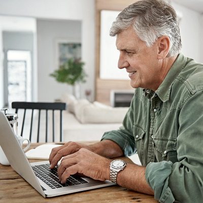 Cropped shot of a mature man working on his laptop at home