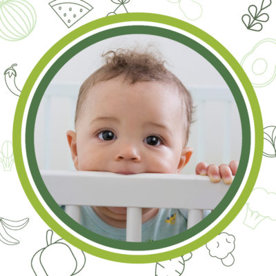 A photo of a baby in a crib looking over the protection rail.