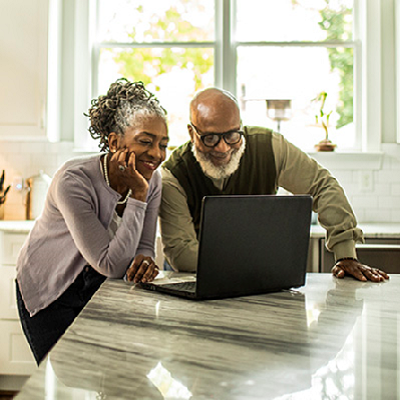 An older couple reviewing information on a laptop in the kitchen