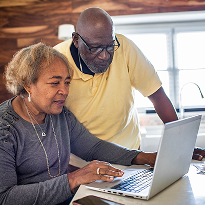 An elderly couple looking at a laptop screen.